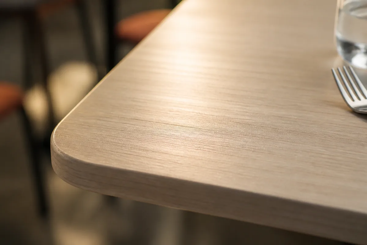 Gros plan sur un plateau de table en stratifié compact, surface lisse et texture professionnelle